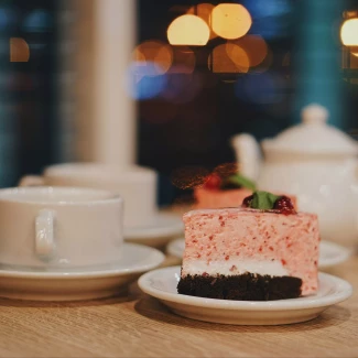 białe filiżanki, ciasto owocowe i imbryk w tle