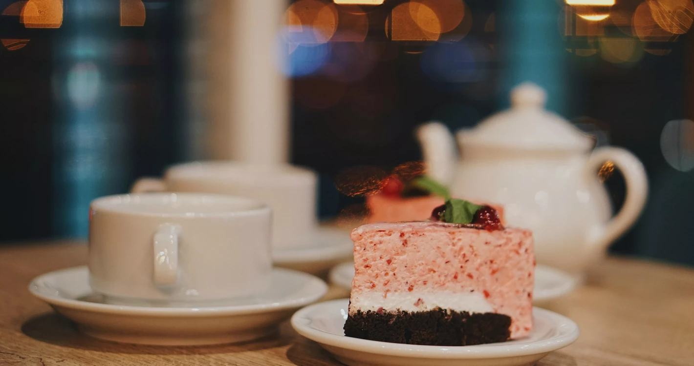 białe filiżanki, ciasto owocowe i imbryk w tle