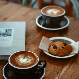dwie czarne filiżanki kawy i ciastko na stole