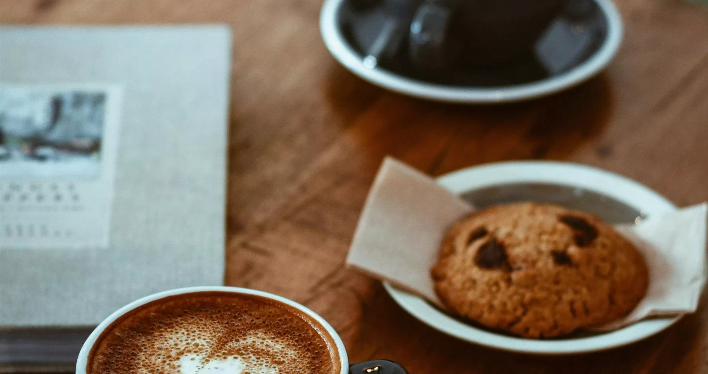 dwie czarne filiżanki kawy i ciastko na stole